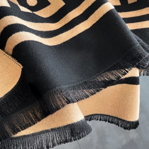 Sciarpa spessa a quadri neri e beige con motivi geometrici e dettagli di frange