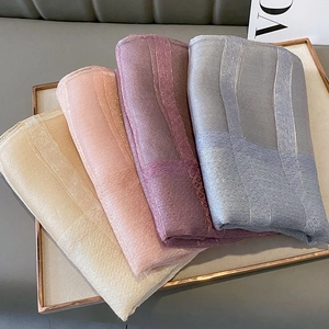 Detailed view of silk-blend scarves in four colors with shimmering jacquard patterns