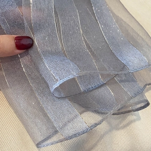 Detail of grey-blue silk blend scarf with golden vertical metallic stripes and sheer texture