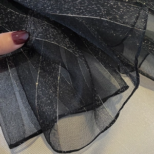Detailed macro view of black mesh fabric with vertical silver metallic tinsel embroidery