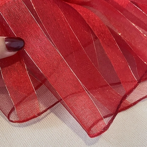 Close-up of red silk blend scarf with vertical gold stripes and fine hemmed edges