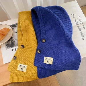 Détail de la maille d'un bonnet cagoule jaune et bleu avec des boutons décoratifs