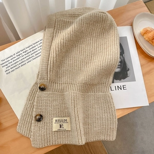 Cagoule balaclava beige en maille épaisse avec boutons sur un fond d'automne douillet
