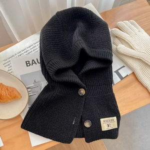 Détail de la cagoule en tricot côtelé noir avec boutons et étiquette sur table en bois