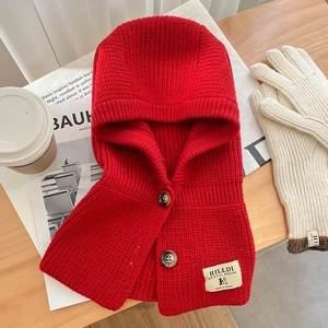 Détail d'écharpe à capuche en tricot rouge avec boutons et patch de créateur sur bois