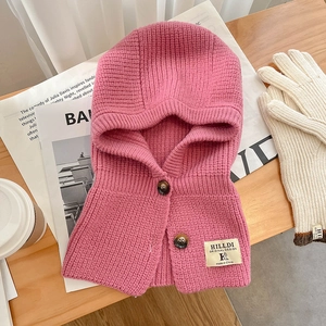 Vue détaillée d'une écharpe à capuche en tricot rose avec boutons et gants crème