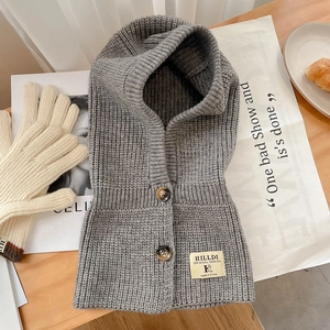 Détail d'une capuche en tricot gris avec boutons en bois et étiquette de la marque