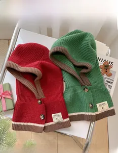 Detaillierte Strickstruktur und Knopfverschluss an Winterkapuzen mit Festtagsdeko