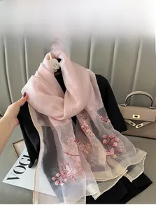 Close-up of silk blend scarf showing elegant pink floral embroidery and smooth texture