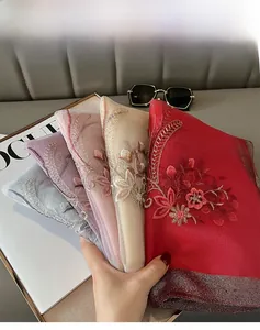 Detailed macro view showing delicate floral embroidery on various colored silk shawls
