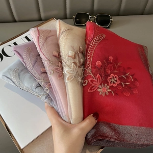 Detail of premium silk blend scarves featuring intricate floral embroidery in multiple colors