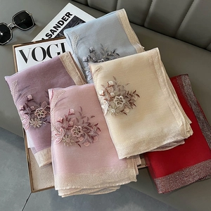 Close-up of silk blend scarves featuring 3D floral embroidery and metallic glitter edges