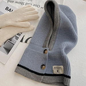 Detail der blauen Strick-Balaclava mit Dekoknöpfen und kontrastgrauem Saumdesign