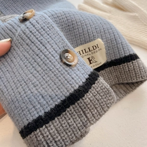Detail der Strickmütze mit Farblock-Design, bernsteinfarbenen Knöpfen und Webeetikett