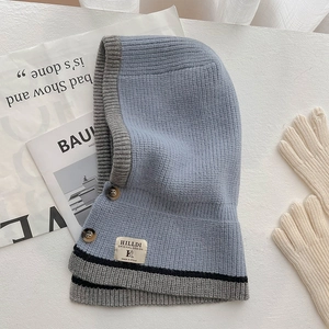 Detailansicht eines hellblauen Strick-Kapuzenschals mit braunen Knöpfen und Markenlogo