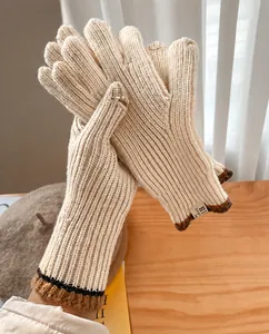 Detalle de guantes de punto gruesos con colores en contraste y etiqueta de tela HI