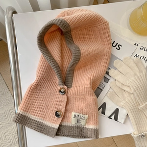 Rosa und graue Strick-Balaclava mit Knöpfen und Markenetikett auf dem Tisch