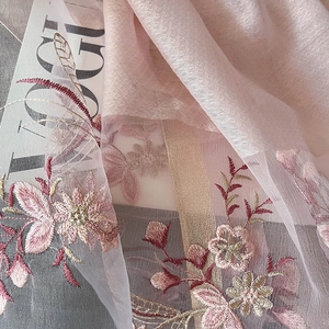 Macro shot of pink embroidered silk blend fabric with floral patterns and gold thread