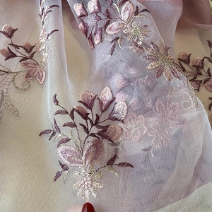 Close-up detail of floral embroidery on elegant silk blend semi-transparent scarf fabric