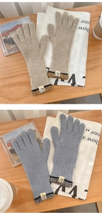 Dettaglio di guanti in maglia a coste beige e blu con etichette su tavolo in legno