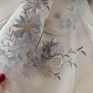 Close-up of intricate gold and purple floral embroidery on a sheer silk blend scarf