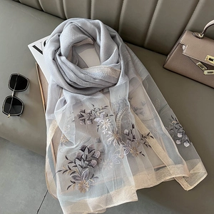 Detailed close-up of grey-blue silk blend scarf with exquisite floral embroidery and sequins