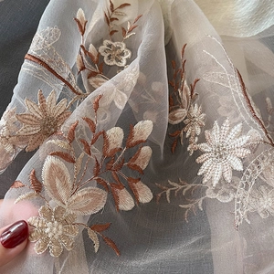 Close-up of intricate floral embroidery on semi-transparent silk blend scarf fabric