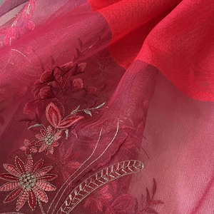 Macro shot of fine red floral embroidery on elegant translucent silk blend fabric