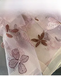 Détail d'écharpe en soie et laine lilas avec broderie florale et bordure finie