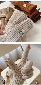 Close-up of ribbed knit gloves with touchscreen finger openings and brand label
