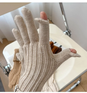 Detail of beige knitted gloves featuring thumb and index finger openings for touchscreen use