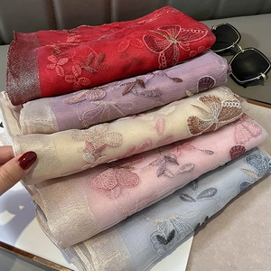 Détail de la broderie florale sur écharpes légères en soie et laine avec bordures métallisées