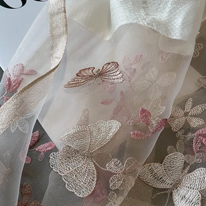 Macro de broderie de papillon délicate sur écharpe en soie et laine blanche