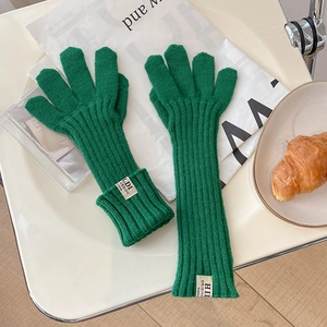 Detailed macro view of green knit gloves with white logo tag and ribbed texture