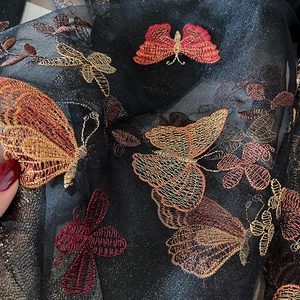 Détail de broderies papillons colorées sur un tissu en maille de soie noire élégant