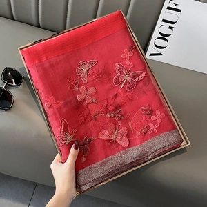 Détail d'un châle rouge en soie et laine avec broderie papillon et bordure métal