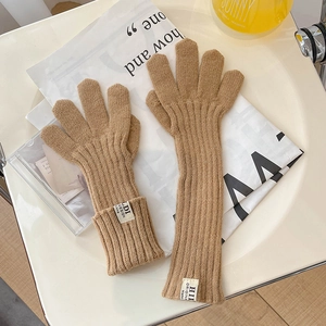 Close-up of camel knit gloves with ribbed texture on a decorative tray background