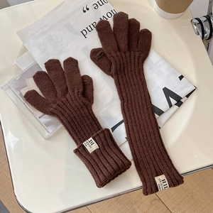 Detail of brown ribbed knit gloves with decorative white label on a styled background