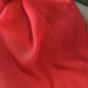 Texture détaillée de l'écharpe en soie et laine rouge montrant des motifs à petits pois
