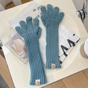 Macro view of blue-grey rib-knitted gloves with a decorative woven label
