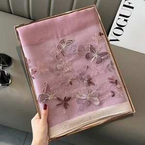 Détail d'une écharpe en soie et laine rose brodée de papillons avec texture en maille