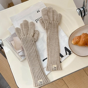 Detail of beige knitted gloves with ribbed texture and HII label on a white surface