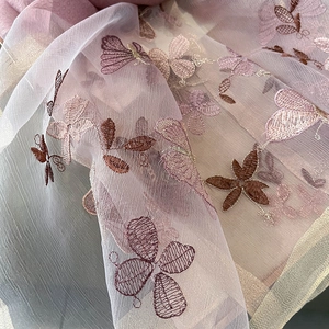 Détail de broderie papillon sur écharpe en soie et laine avec bord doré