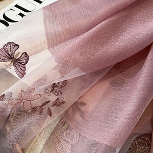 Gros plan d'une broderie papillon sur un tissu translucide en soie et laine