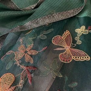 Détail de la broderie fleur et papillon sur écharpe en soie et laine vert foncé