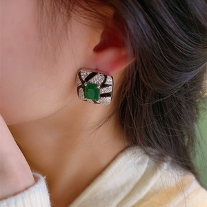 Macro shot of geometric sugar cube earring with green zircon and zebra texture