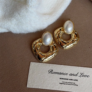 Detailed view of vintage gold quilted earrings with elegant white pearl accents