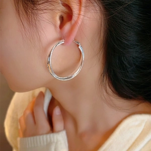 Silver interlocking hoop earrings with matte and polished texture on female model