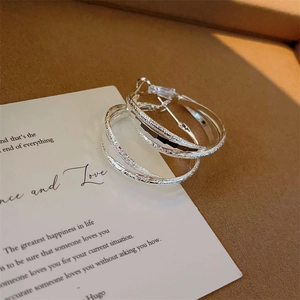 Detail of silver crossover hoop earrings with frosted sand and polished finish