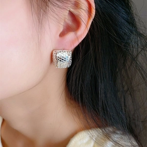 Macro shot of silver hollow cube earrings with honeycomb texture on a model